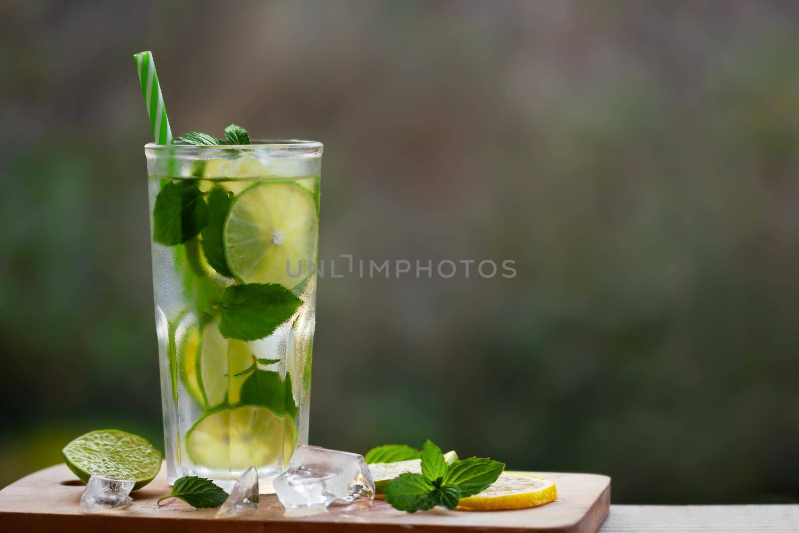 Cold refreshing homemade lemonade with mint, lemon and lime in a glass, copyspace.