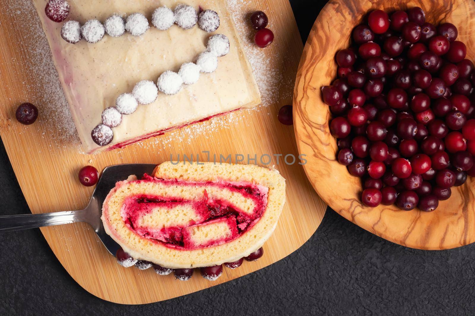 Homemade biscuit sweet roll with cranberries and cream on a black table, top view, flat lay by galsand