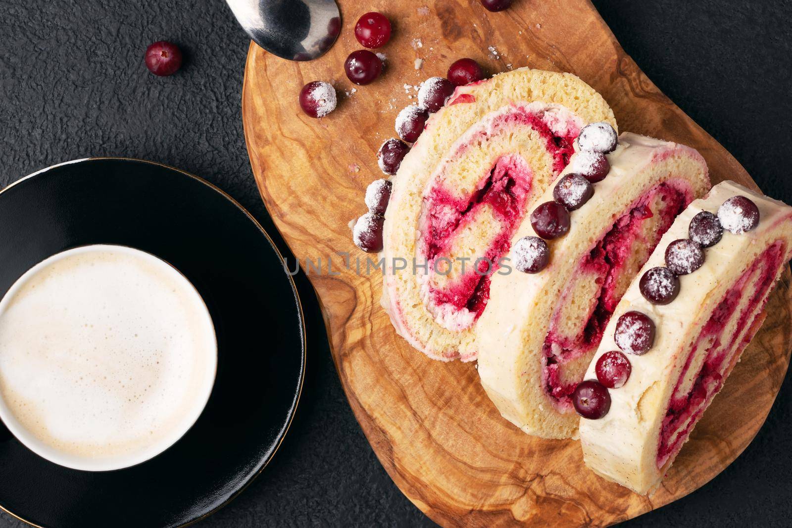 Homemade biscuit sweet roll with cranberries and cream on a black table, top view, flat lay by galsand