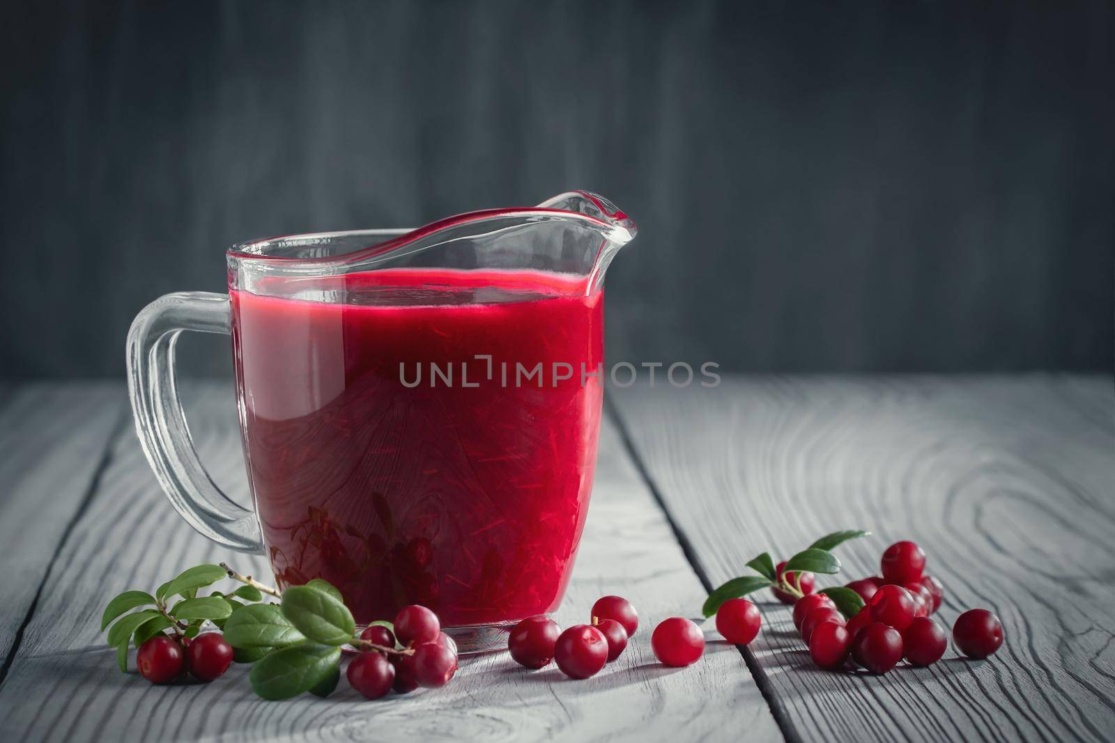 Homemade fresh wild lingonberry sauce in a glass gravy boat, copy space.