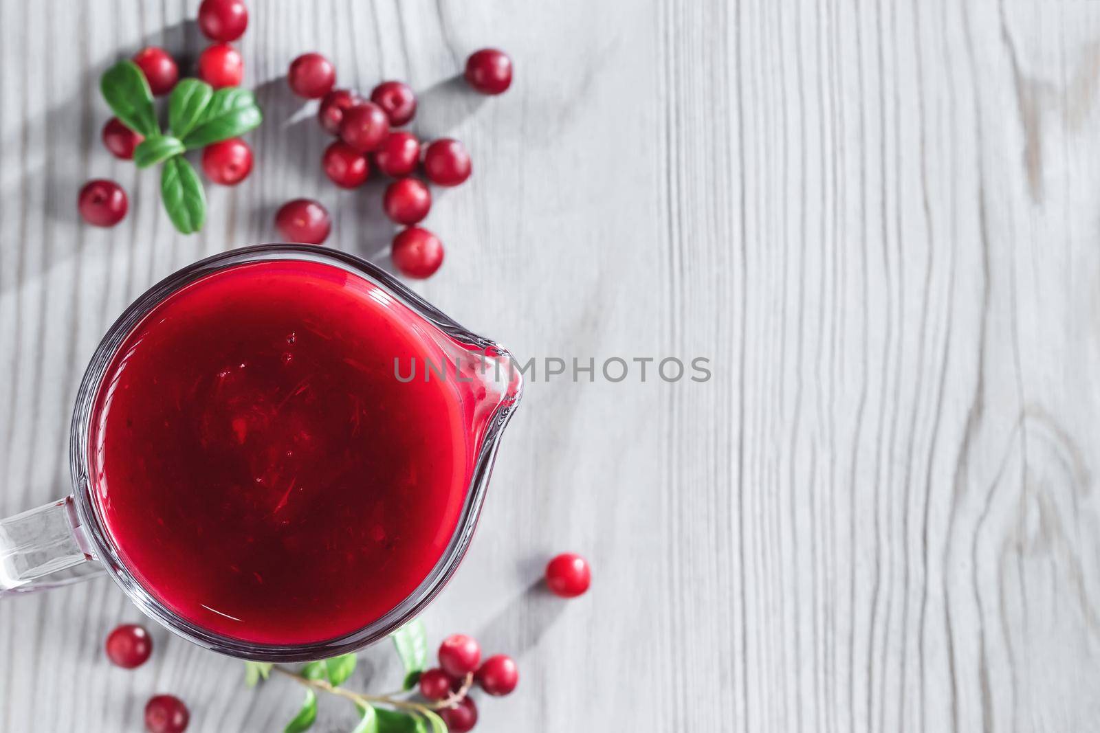 Homemade fresh wild lingonberry sauce in a glass gravy boat, top view, flat lay, copyspace by galsand