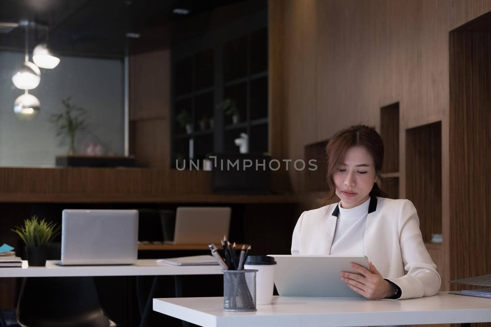 Young asian female in business suit using on digital tablet at her office.