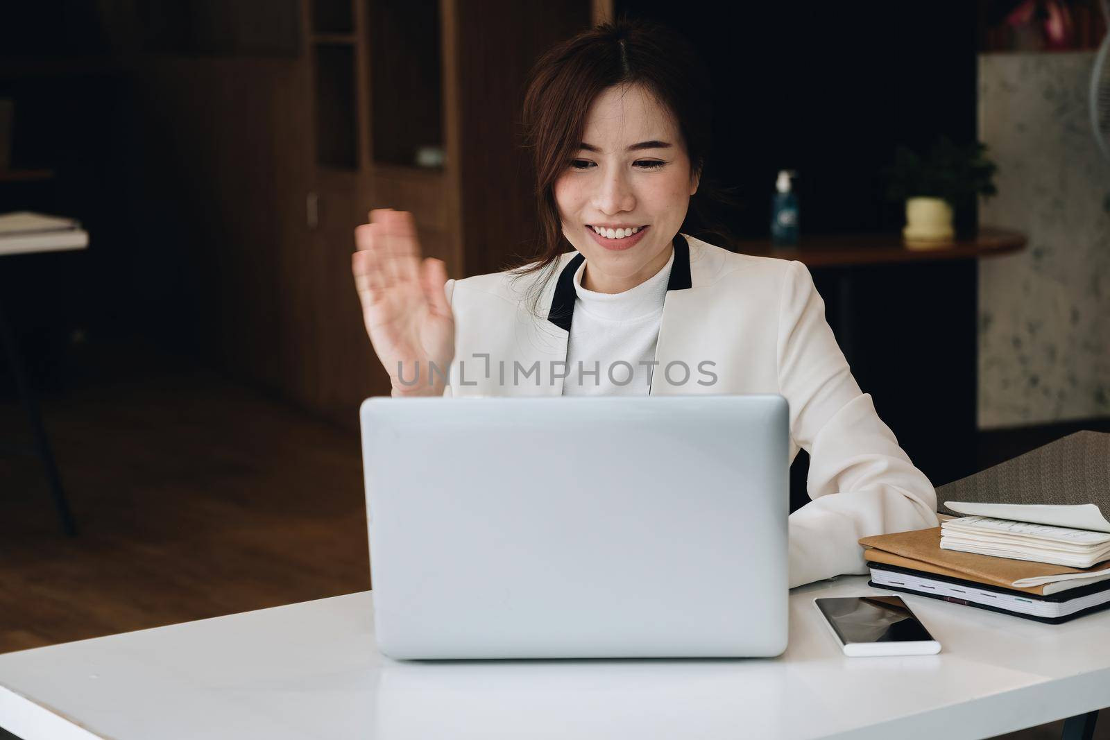 Video call concept, young business woman using a laptop for video connection with family, remote meeting, say hi, looking at the webcam