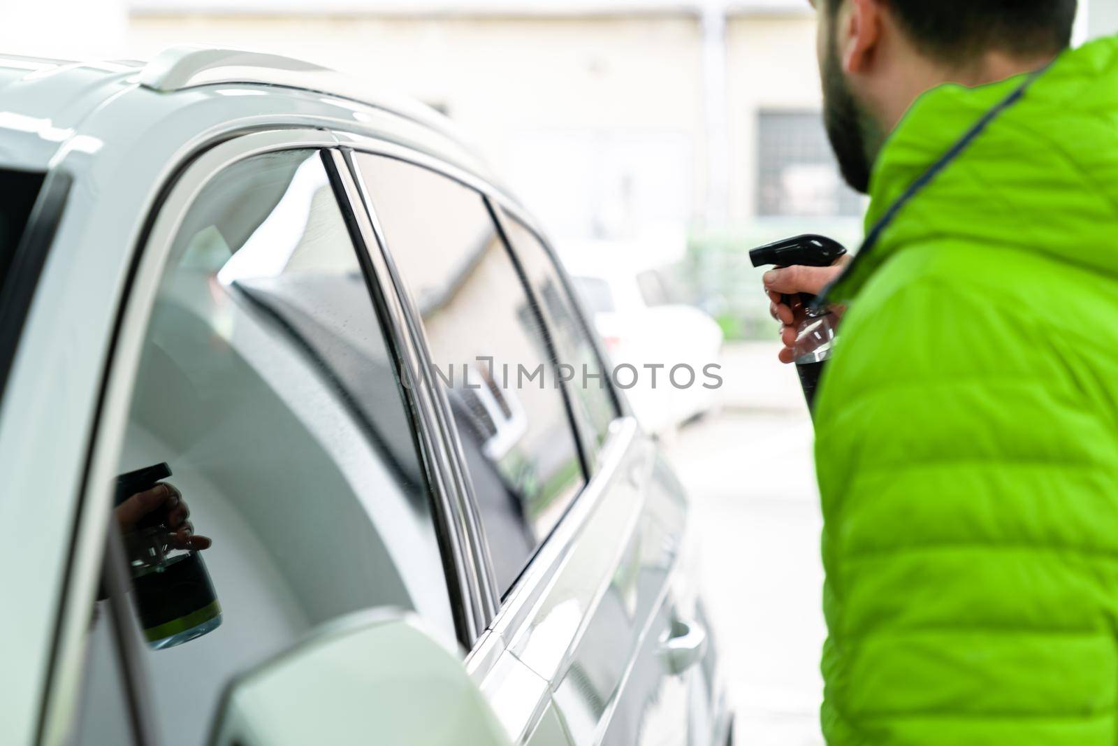 man cleans the car glass with a sprayer. auto care by Edophoto