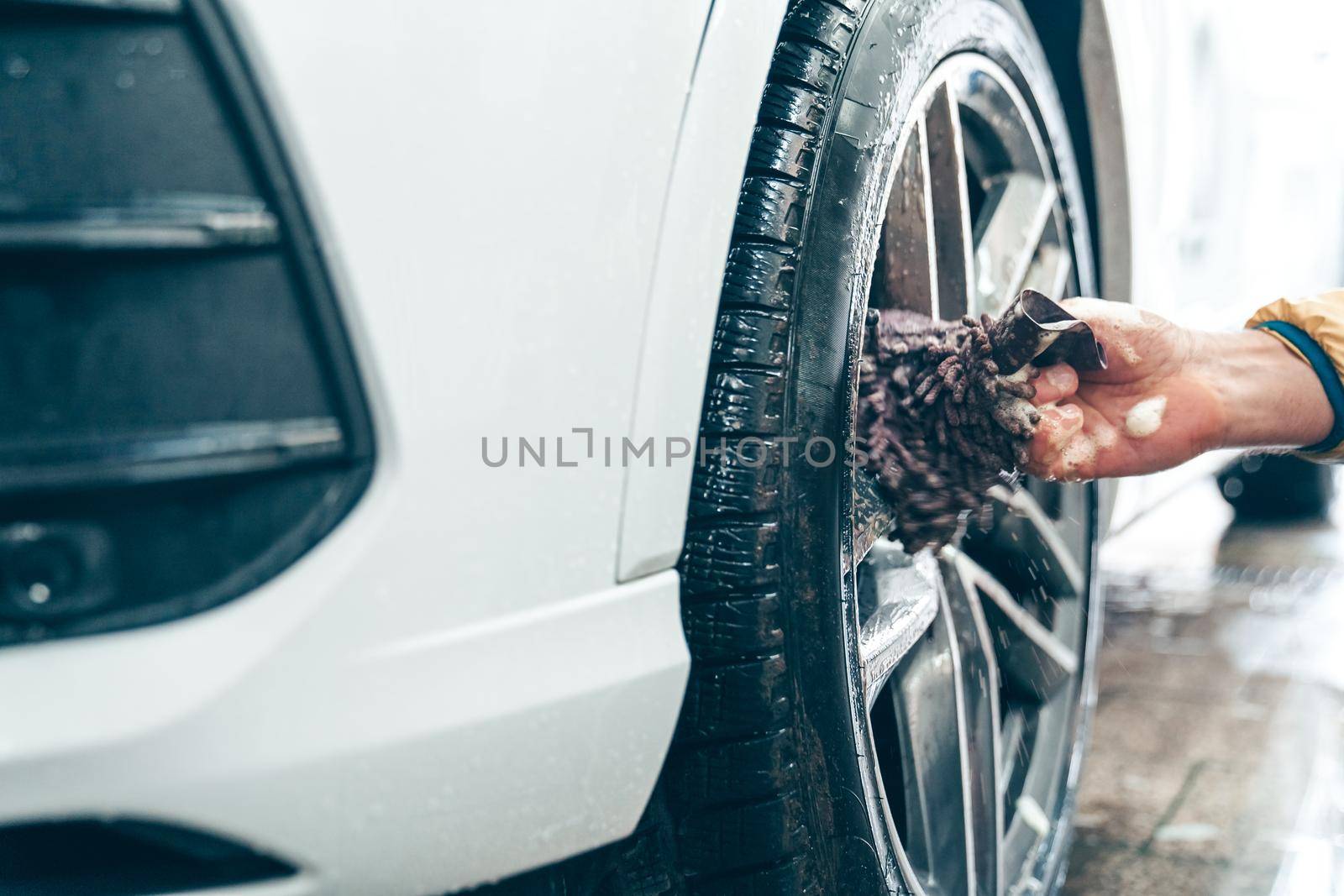 Manual car wheel cleaning with the help of sponges and foam.