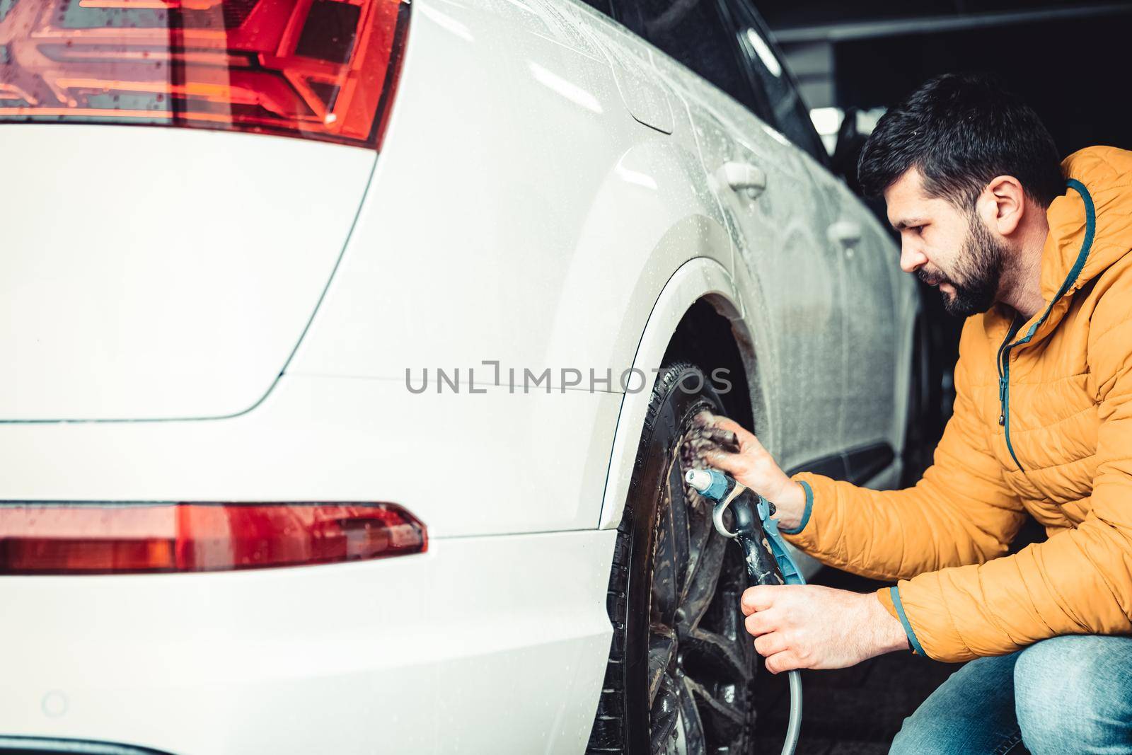 manually wash car wheels using pressure hoses with water.