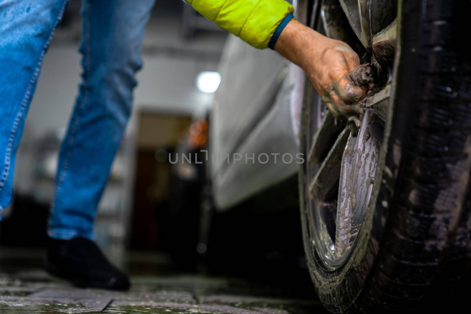 Manual car wheel cleaning with the help of sponges and foam.