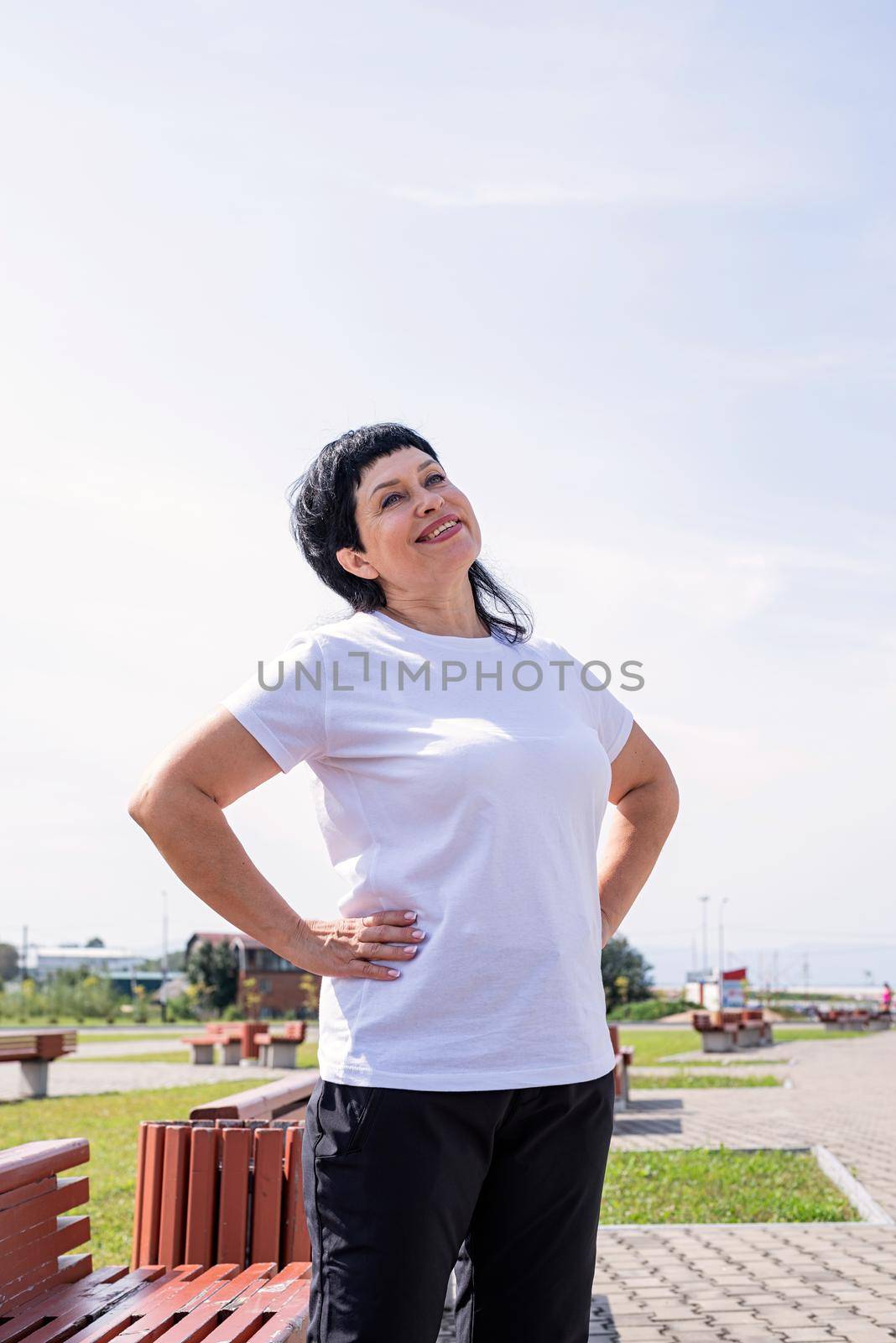 Sport and fitness. Senior sport. Active seniors. Smiling senior woman doing warm up before training outdoors in the park