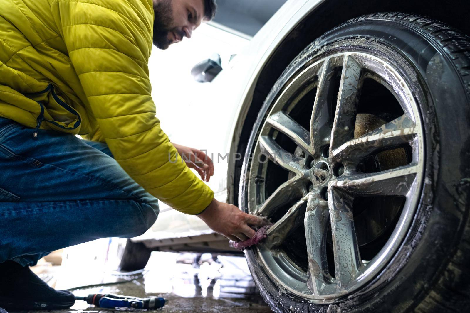 Manual car wheel cleaning with the help of sponges and foam by Edophoto