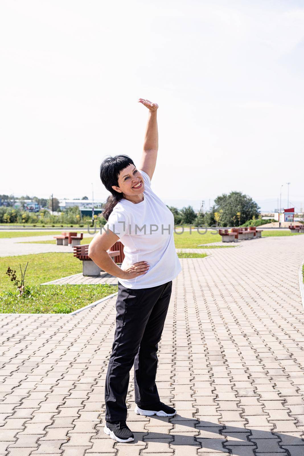 Sport and fitness. Senior sport. Active seniors. Smiling senior woman warming up stretching outdoors in the park
