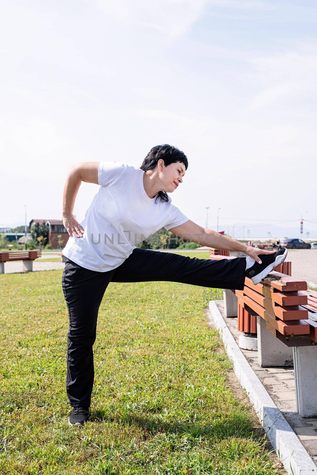 Sport and fitness. Senior sport. Active seniors. Smiling senior woman warming up stretching outdoors in the park