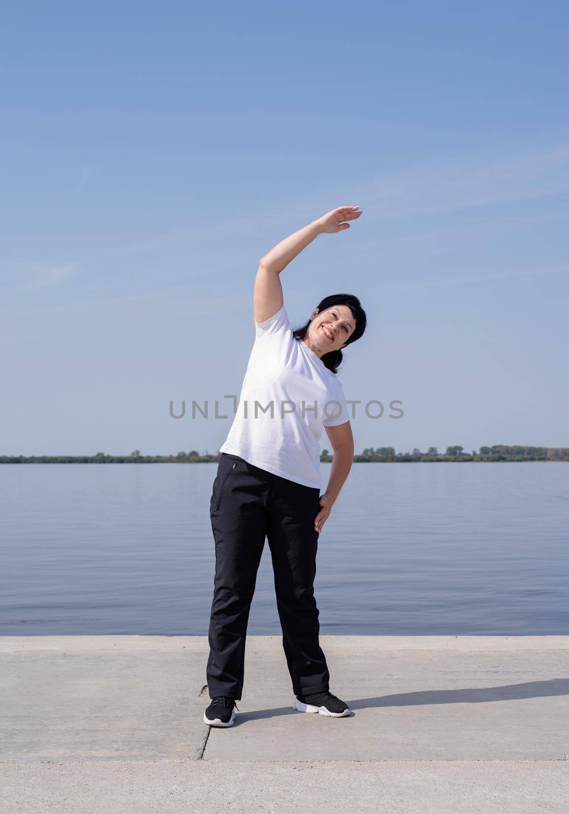 Sport and fitness. Senior sport. Active seniors. Active and happy senior woman exercising near the riverside