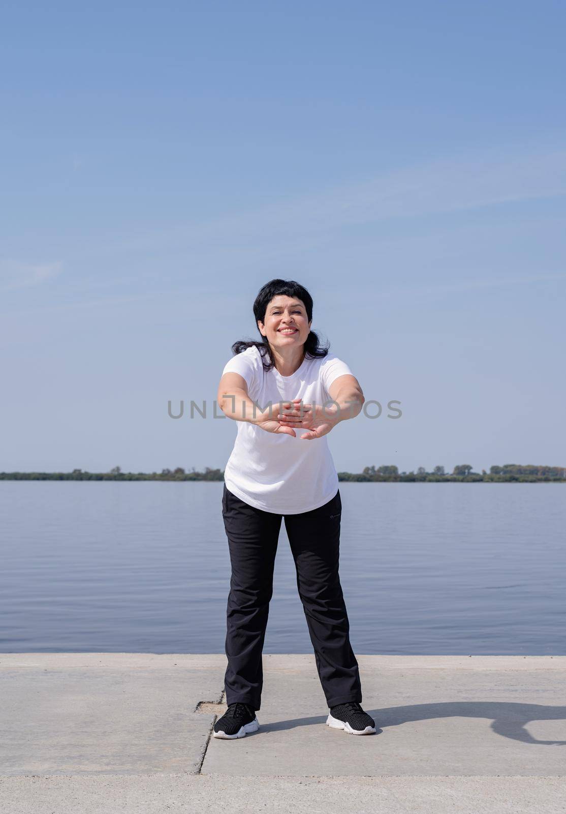 Sport and fitness. Senior sport. Active seniors. Active and happy senior woman exercising near the riverside