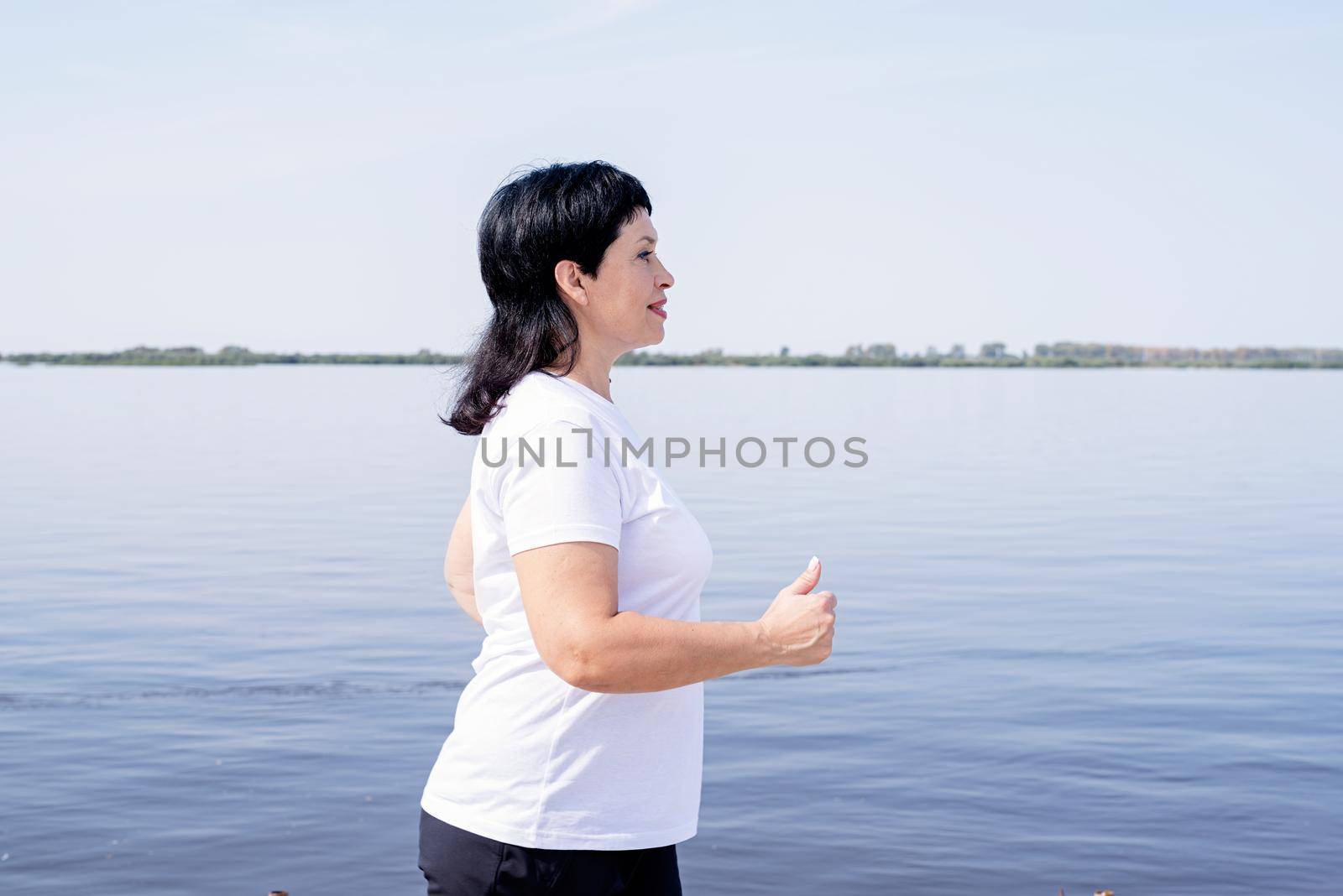 Active senior woman jogging near the riverside by Desperada