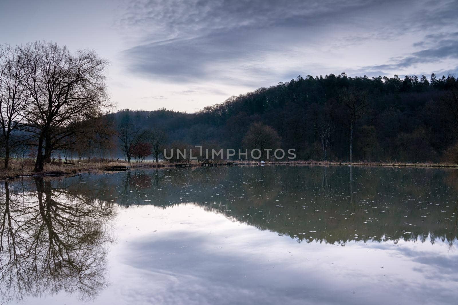 Fishpond close to Lindlar with water reflection during early morning mood, Bergisches Land, Germany