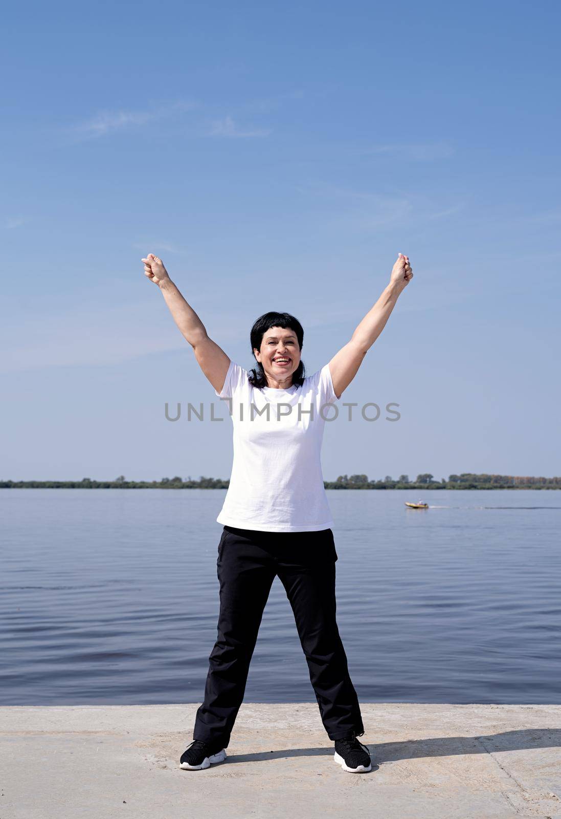 Sport and fitness. Senior sport. Active seniors. Active and happy senior woman exercising near the riverside