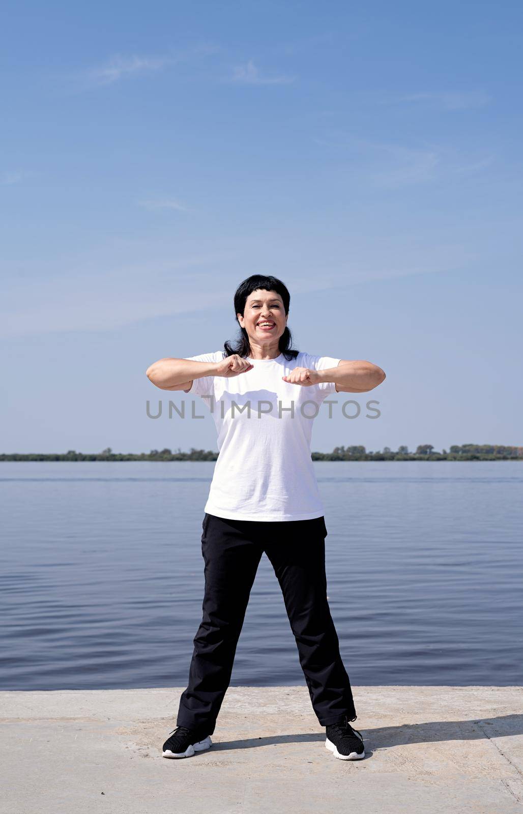 Sport and fitness. Senior sport. Active seniors. Active and happy senior woman exercising near the riverside