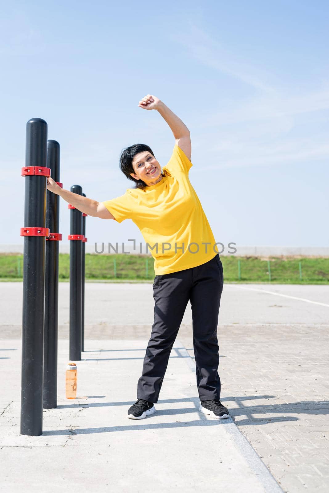 Sport and fitness. Senior sport. Active seniors. Senior woman doing stretching outdoors on the sports ground