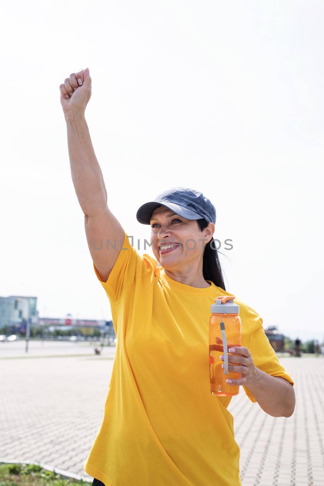 Sport and fitness. Senior sport. Active seniors. Happy senior woman in sports clothes exercising in the park standing with arms up