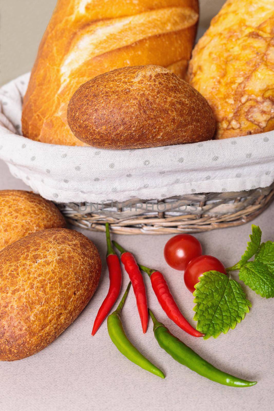Fresh bread in a basket on the table with red peppers and tomatoes. Close-up