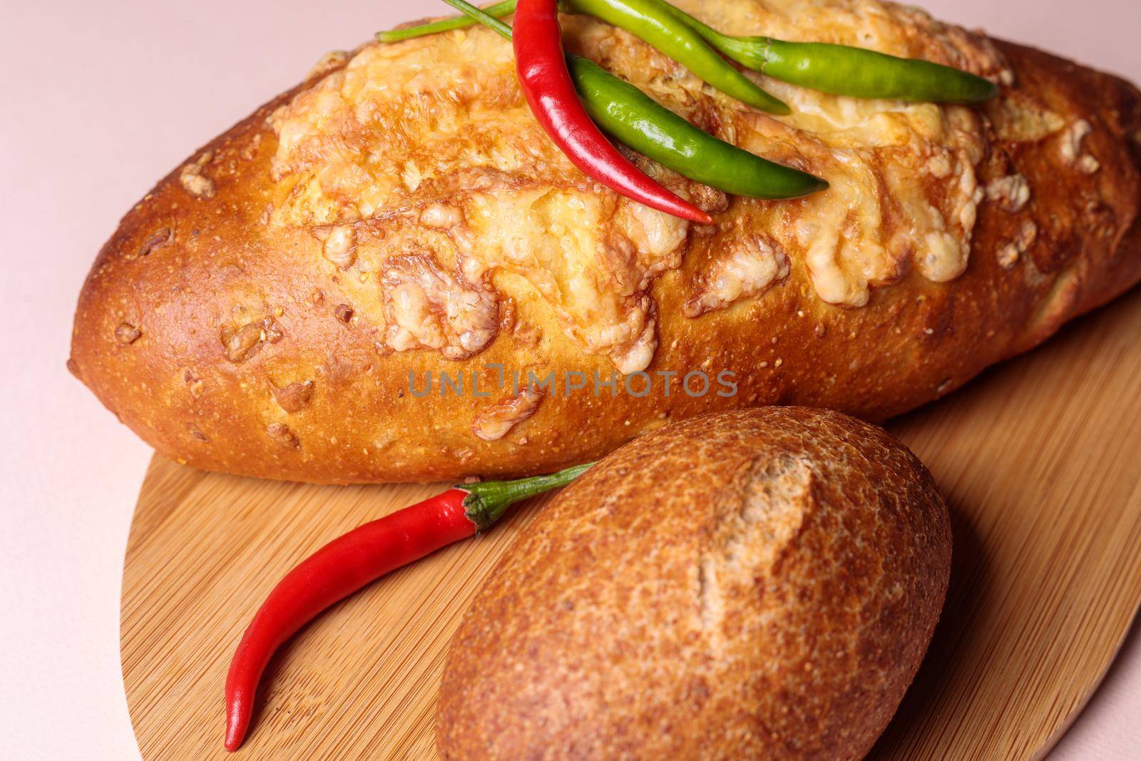 Fresh bread on a cutting board with red and green chili peppers. Close-up