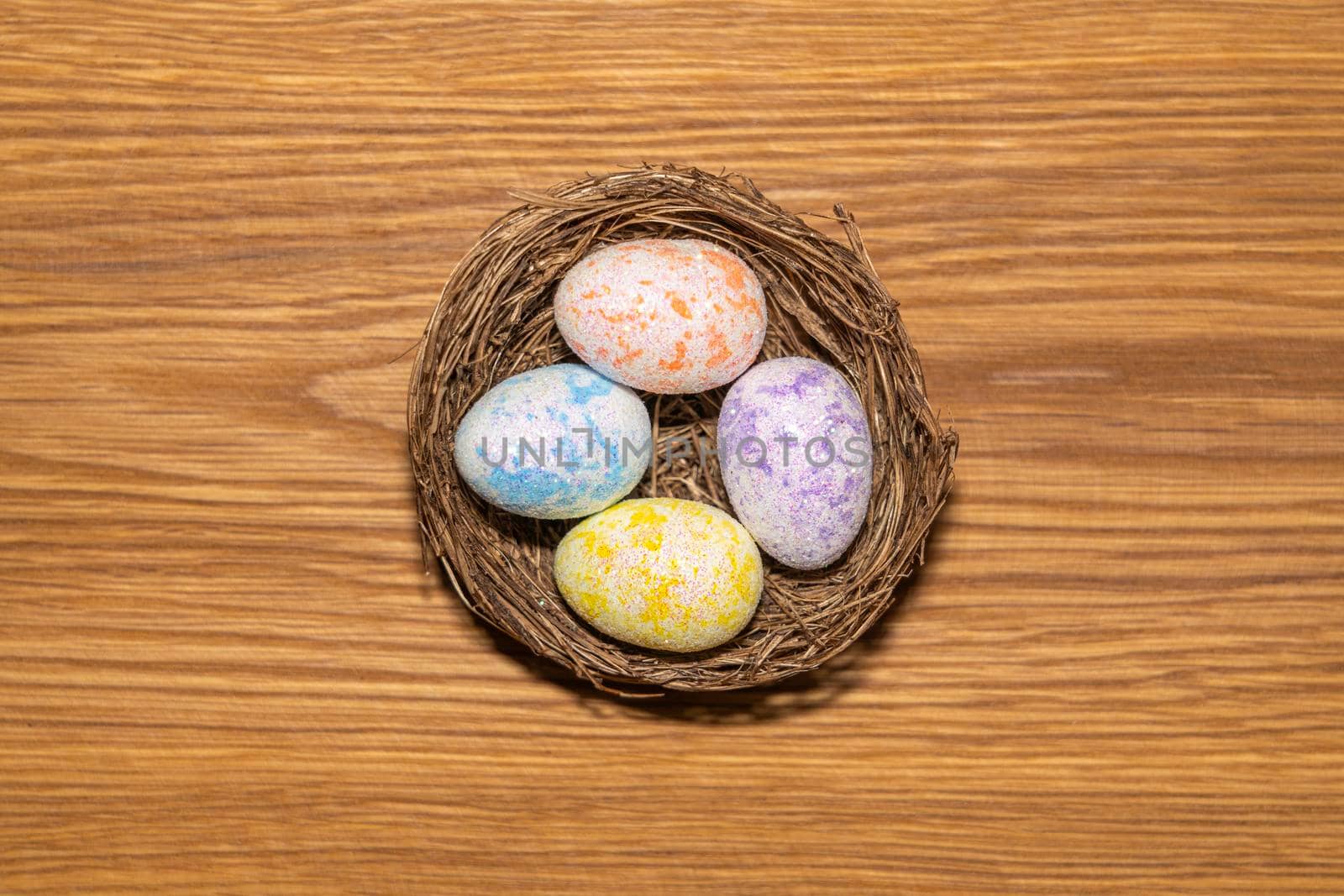 easter colorful eggs in a nest close up on a wooden background. High quality photo