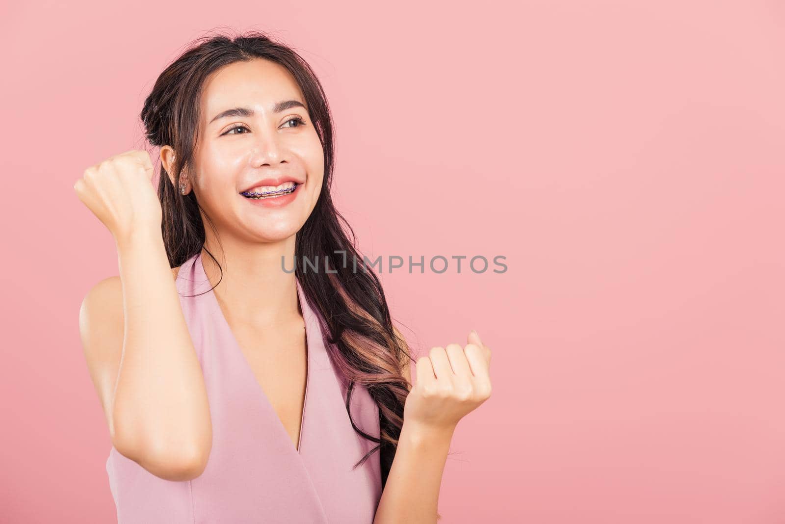 Happy Asian portrait beautiful cute young woman standing winning and surprised excited screaming open mouth raise hands, studio shot isolated pink background, Thai female wow with copy space