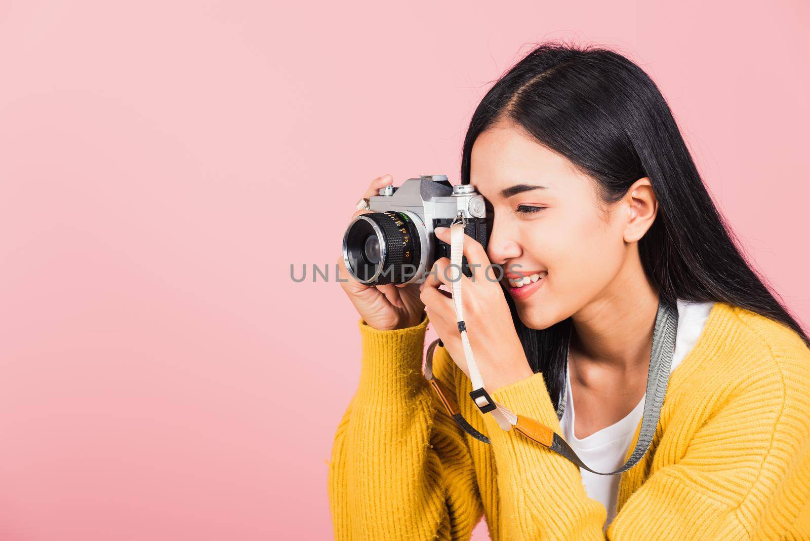 woman smiling photographer taking a picture and looking viewfinder on retro vintage photo camera by Sorapop
