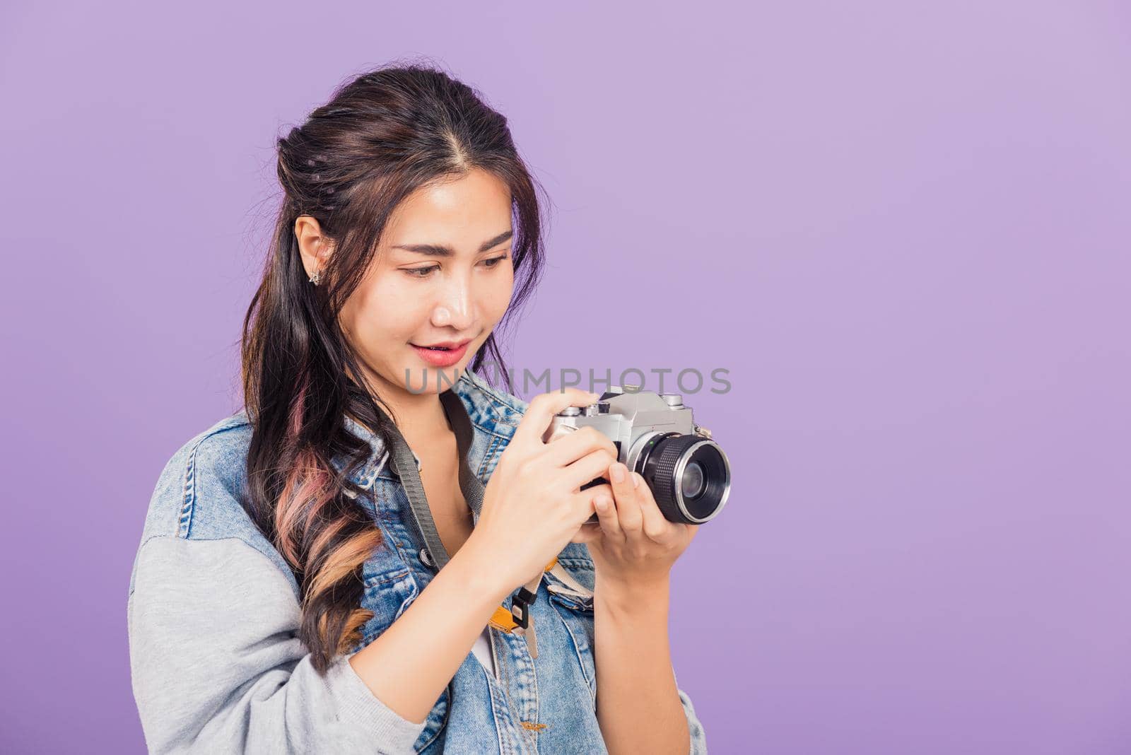 Portrait happy Asian beautiful young woman smiling excited wear denims holding vintage photo camera, teen female traveler female photographer, studio shot isolated on purple background