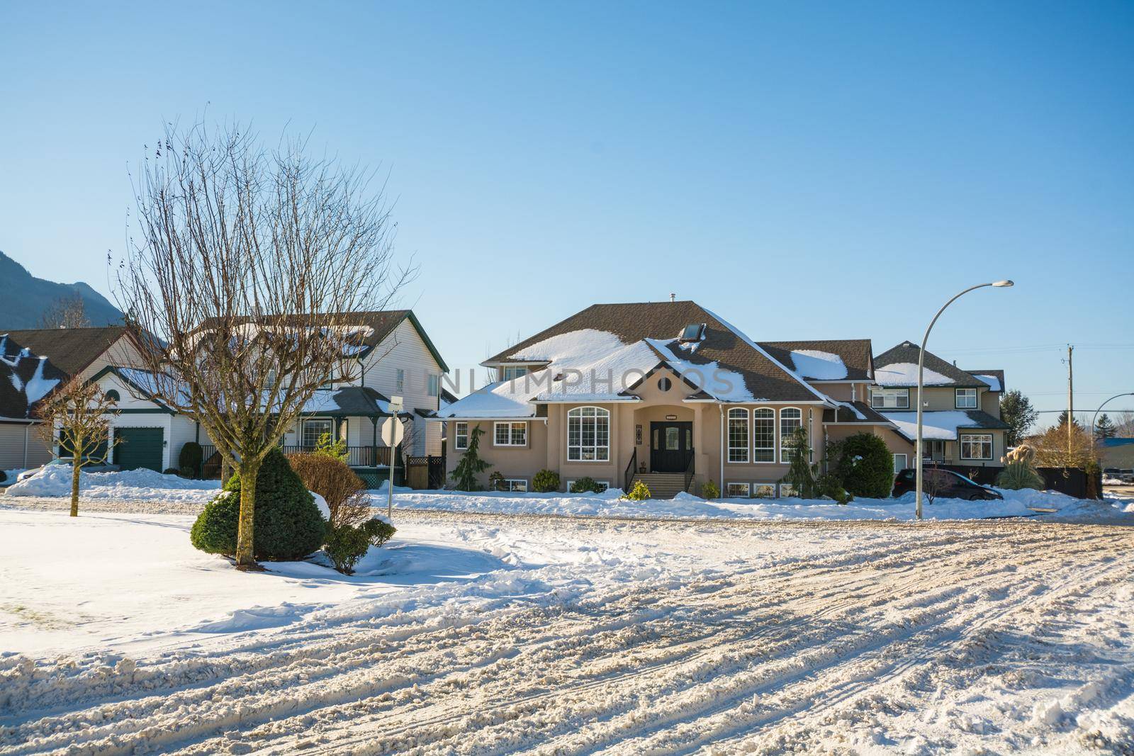 Street of residential houses in snow on winter sunny day. Winter season in suburb in Canada