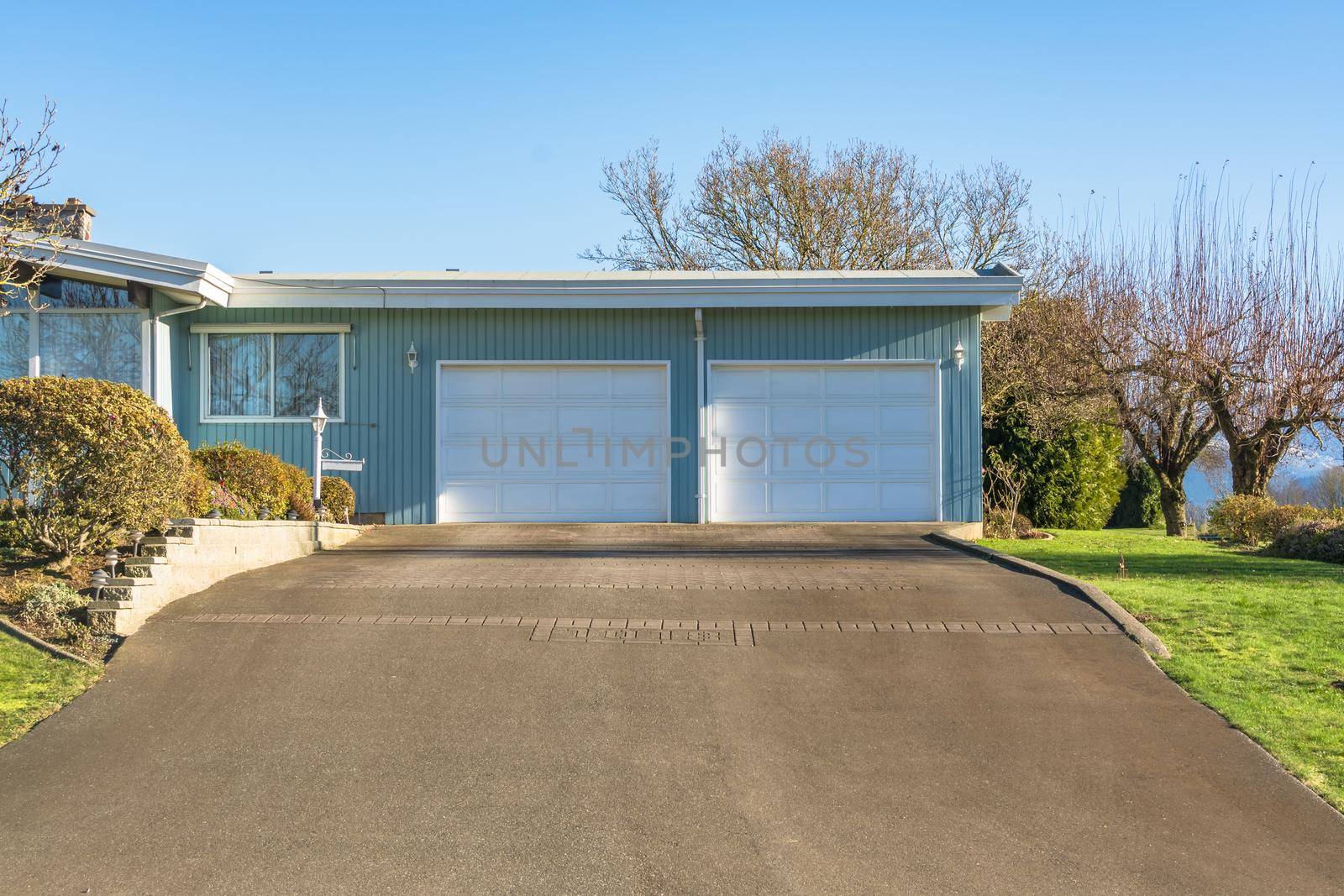 Double gates garage of big residential house with asphalt driveway in front