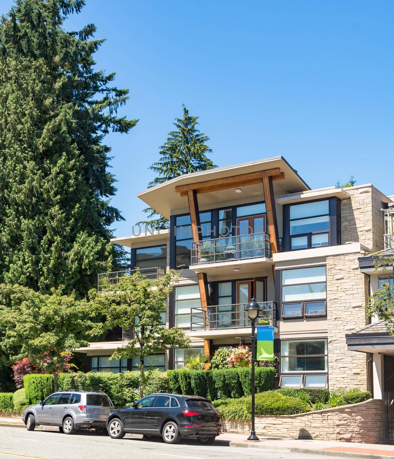 Brand new apartment building with cars parked in front on bright sunny day in British Columbia, Canada.