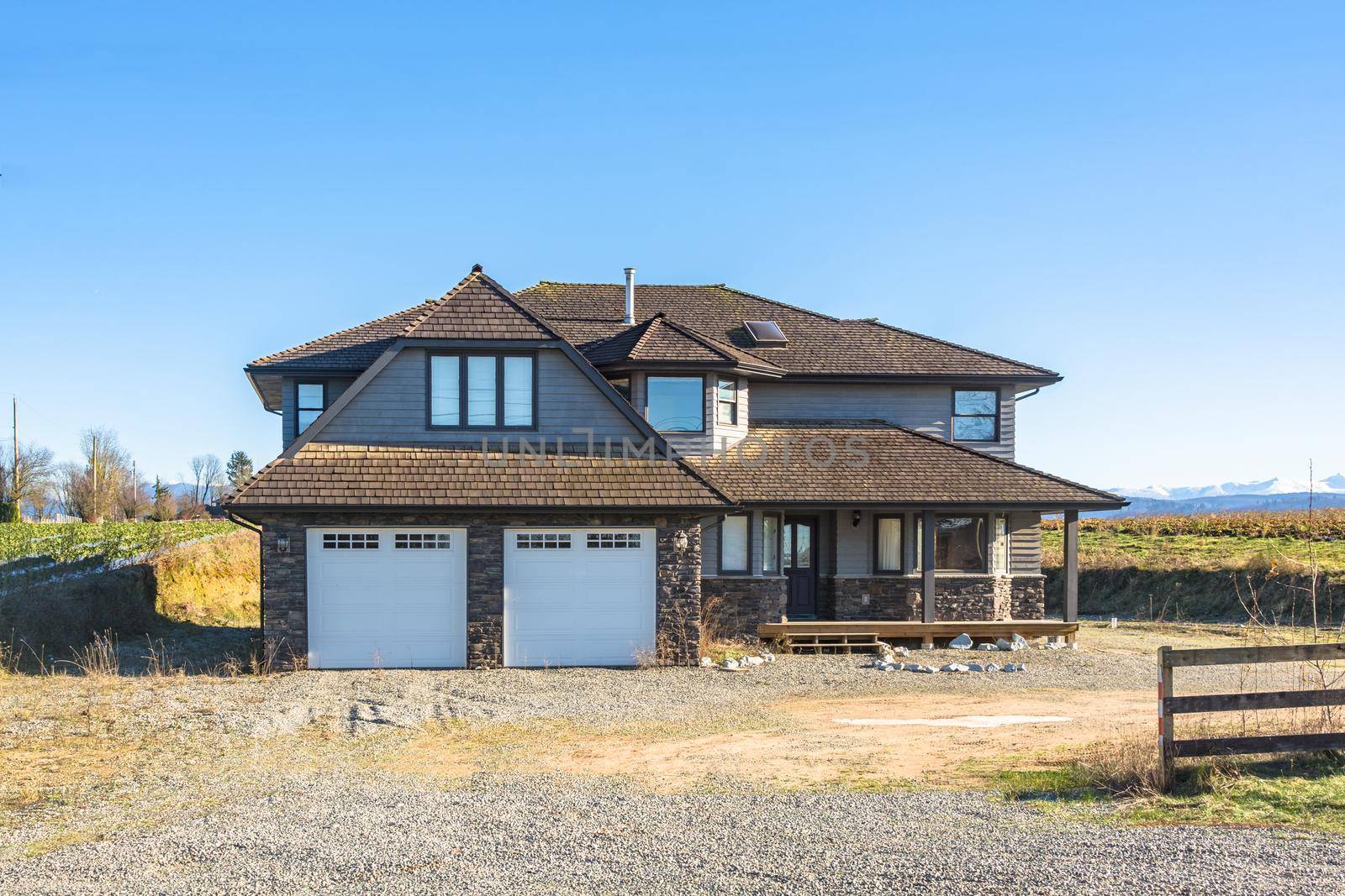 Big residential house on winter sunny day in Canada. New detached house for sale with gravel driveway and front yard without landscaping
