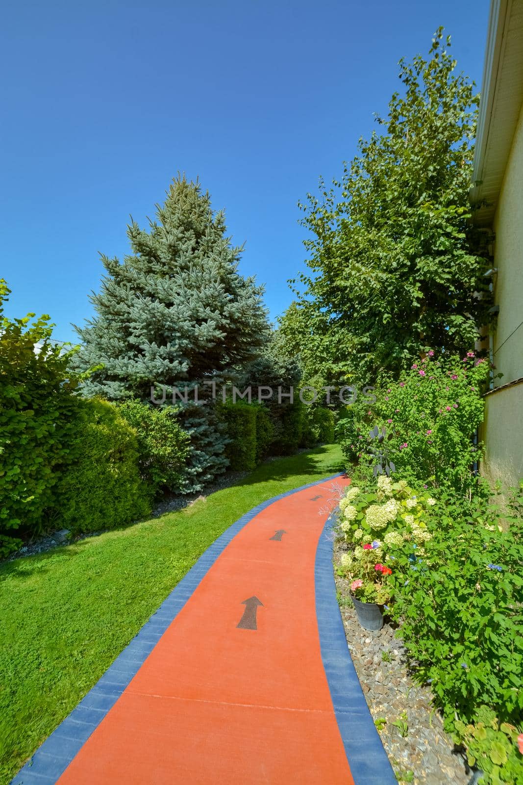 Colored pathway around a house with arrows pointing the direction. Decorated landscape on blue sky background