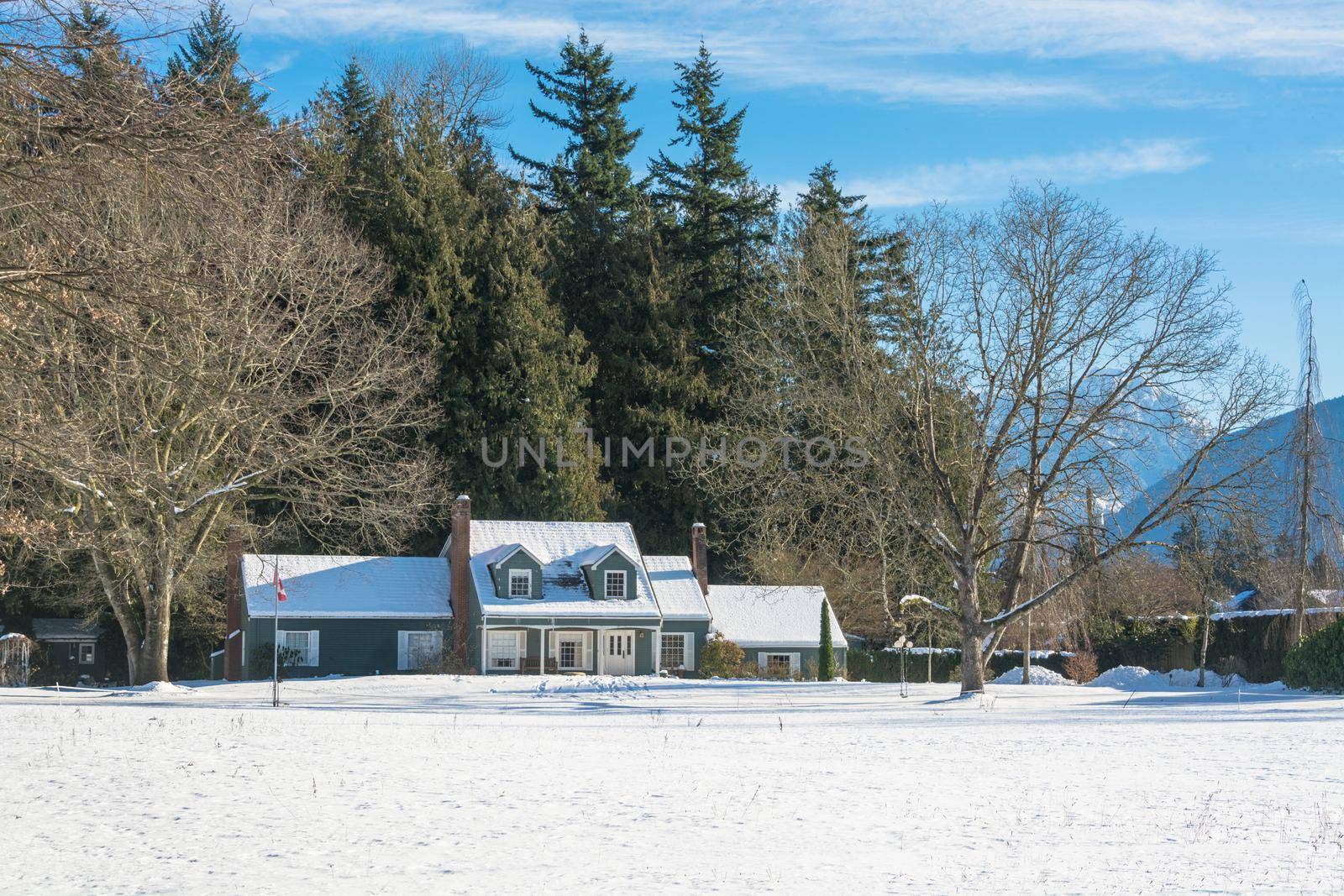Big farmers house with spacious front yard at winter season. Residential house in snow on a sunny day