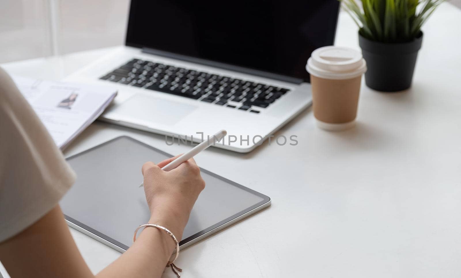 Close up hand of female graphic designer sketching on her project with digital teblet at modern creative workplace.