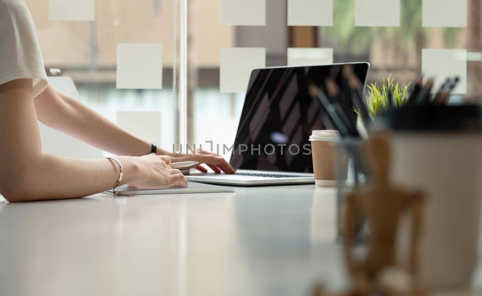 Close up hand of female graphic designer sketching on her project with digital teblet at modern creative workplace.