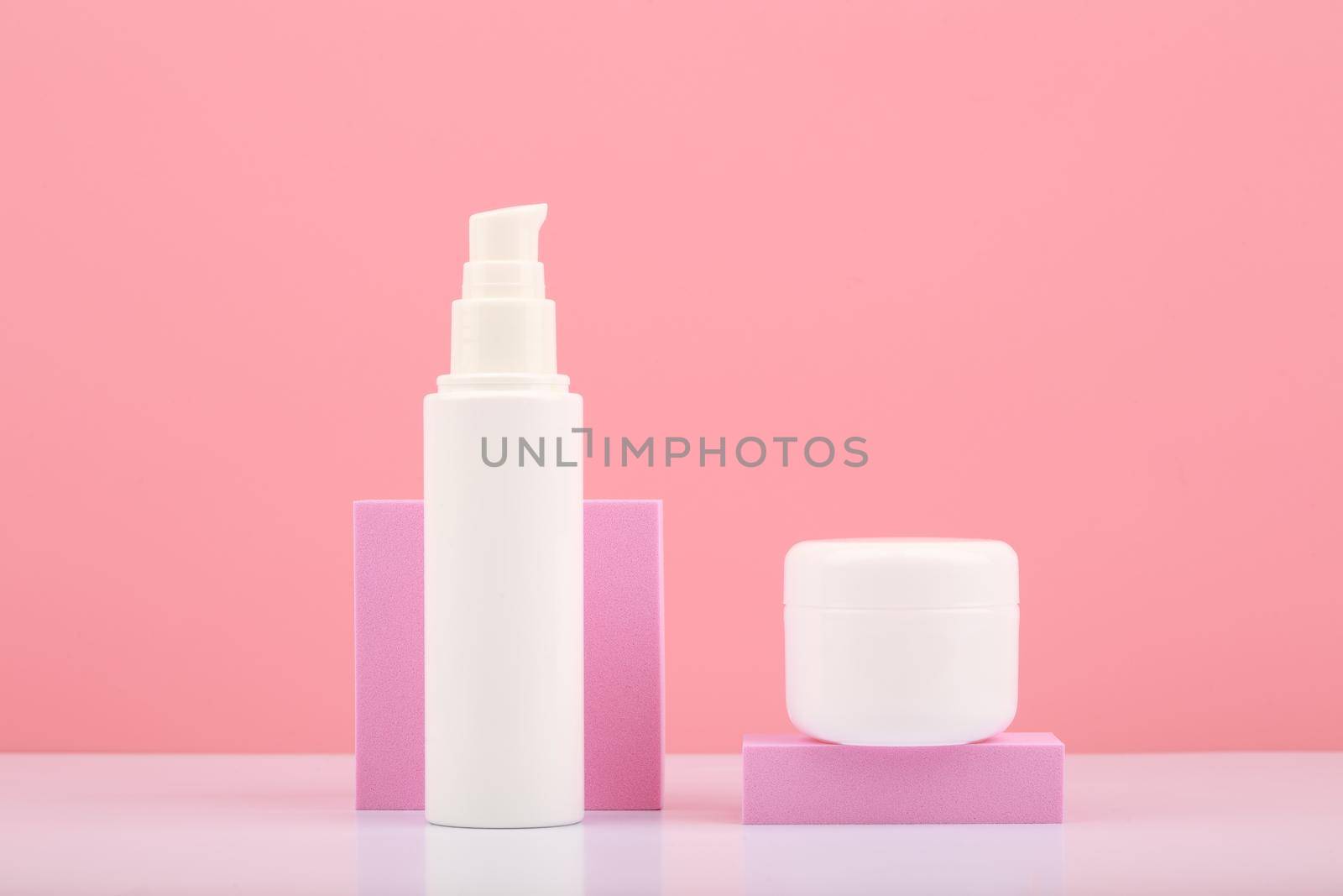 Skin lotion and under eye gel with pink geometric props against pink background by Senorina_Irina