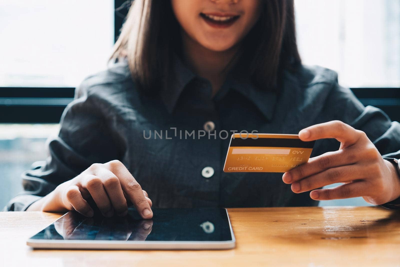 Young woman holding credit card and using tablet computer. Online shopping concept by nateemee