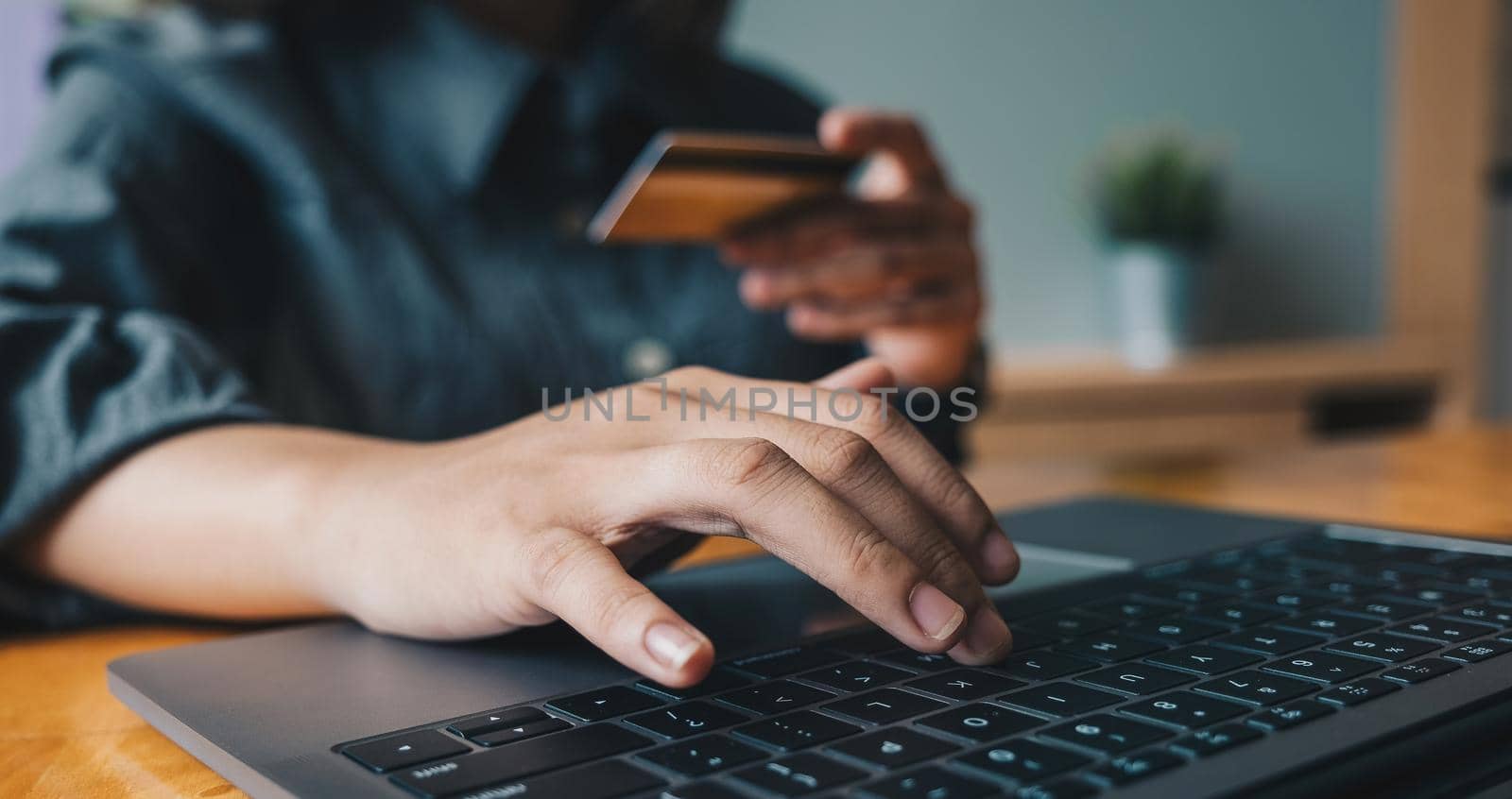 Close up woman at home shopping online with credit card and laptop computer.