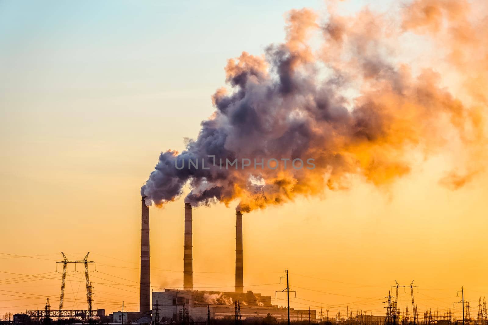 Sunset over the industrial city.Factory chimneys smoke.Environmental problem of environmental and atmospheric pollution.Climate change,environmental disaster.The sky is smoky with toxic substances by YevgeniySam