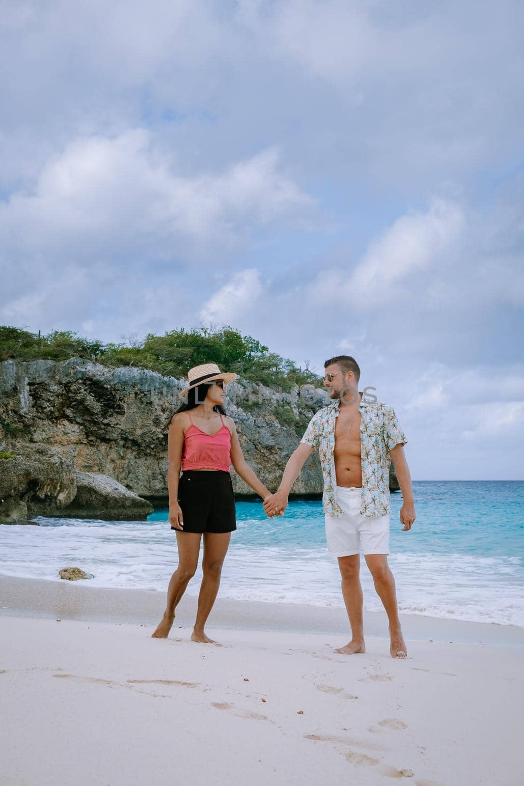 Aerial view of the coast of Curacao in the Caribbean Sea with turquoise water, white sandy beach, coral reef Playa Cas Abao Curacao, couple mid age european man and asian woman during vacation
