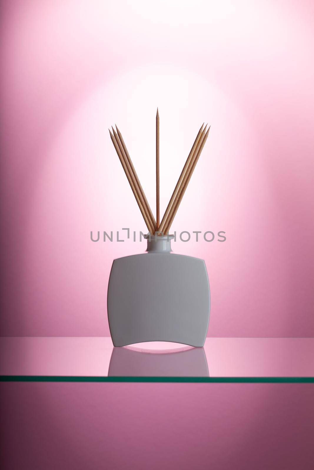 Aromatic reed air freshener on the glass table in the pink bathroom.