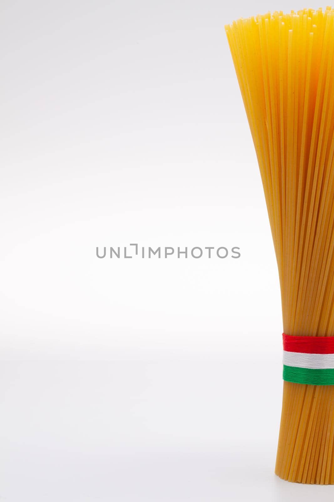 Bundle of spaghetti and Italian flag on the white table by CaptureLight