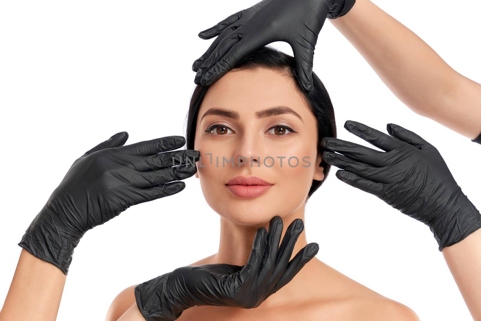 Close up of four hands in black gloves touching woman face by SerhiiBobyk