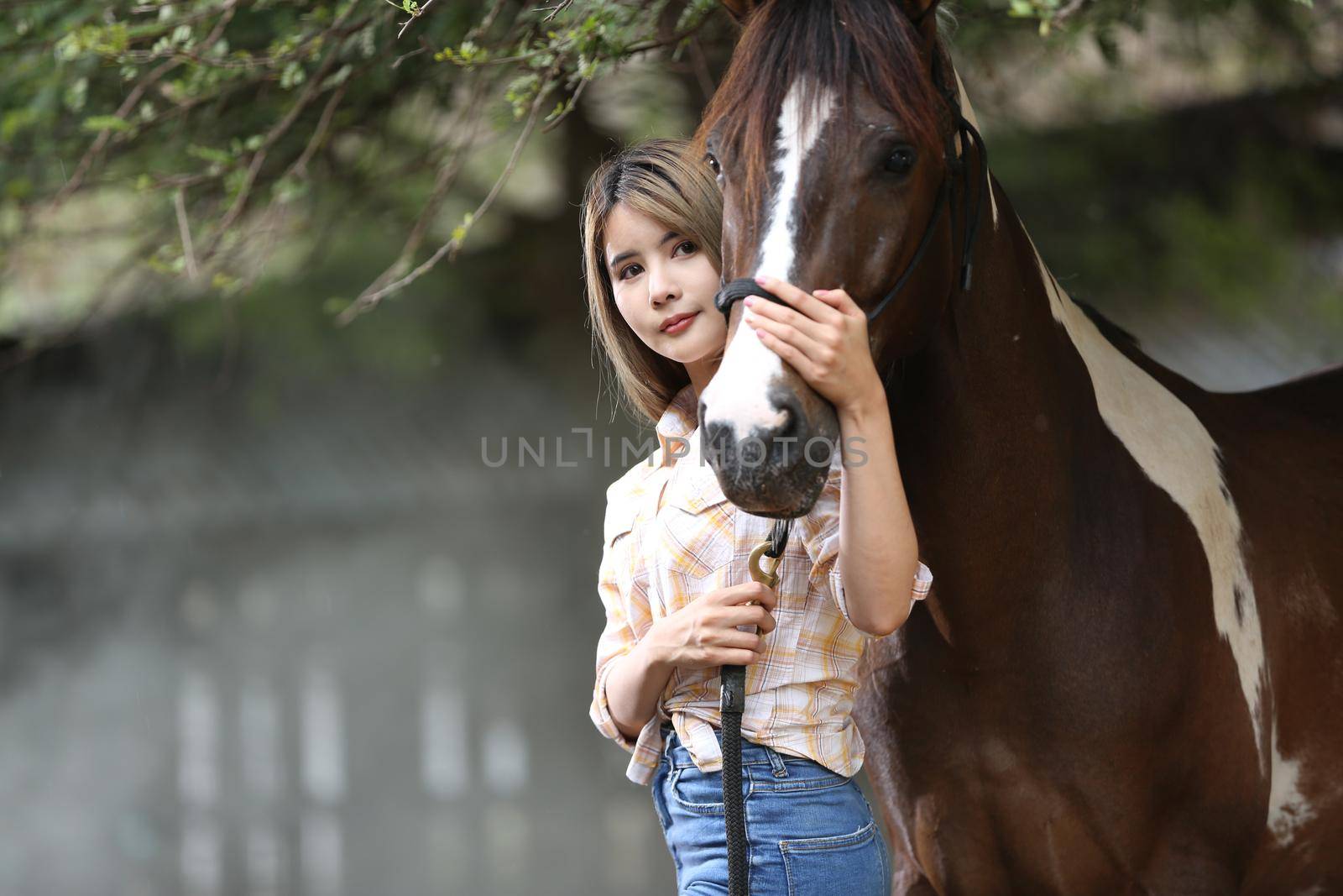 A woman in a cowgirl style sits in a horse ranch with a western farm environment.