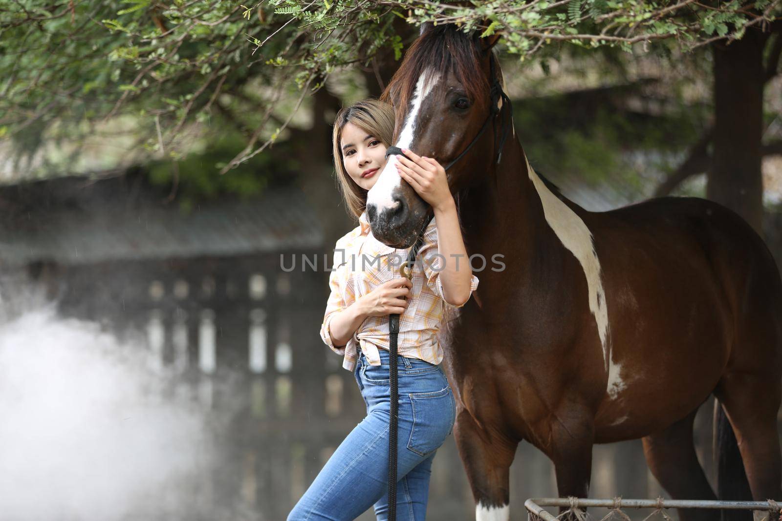 A woman in a cowgirl style sits in a horse ranch with a western farm environment.