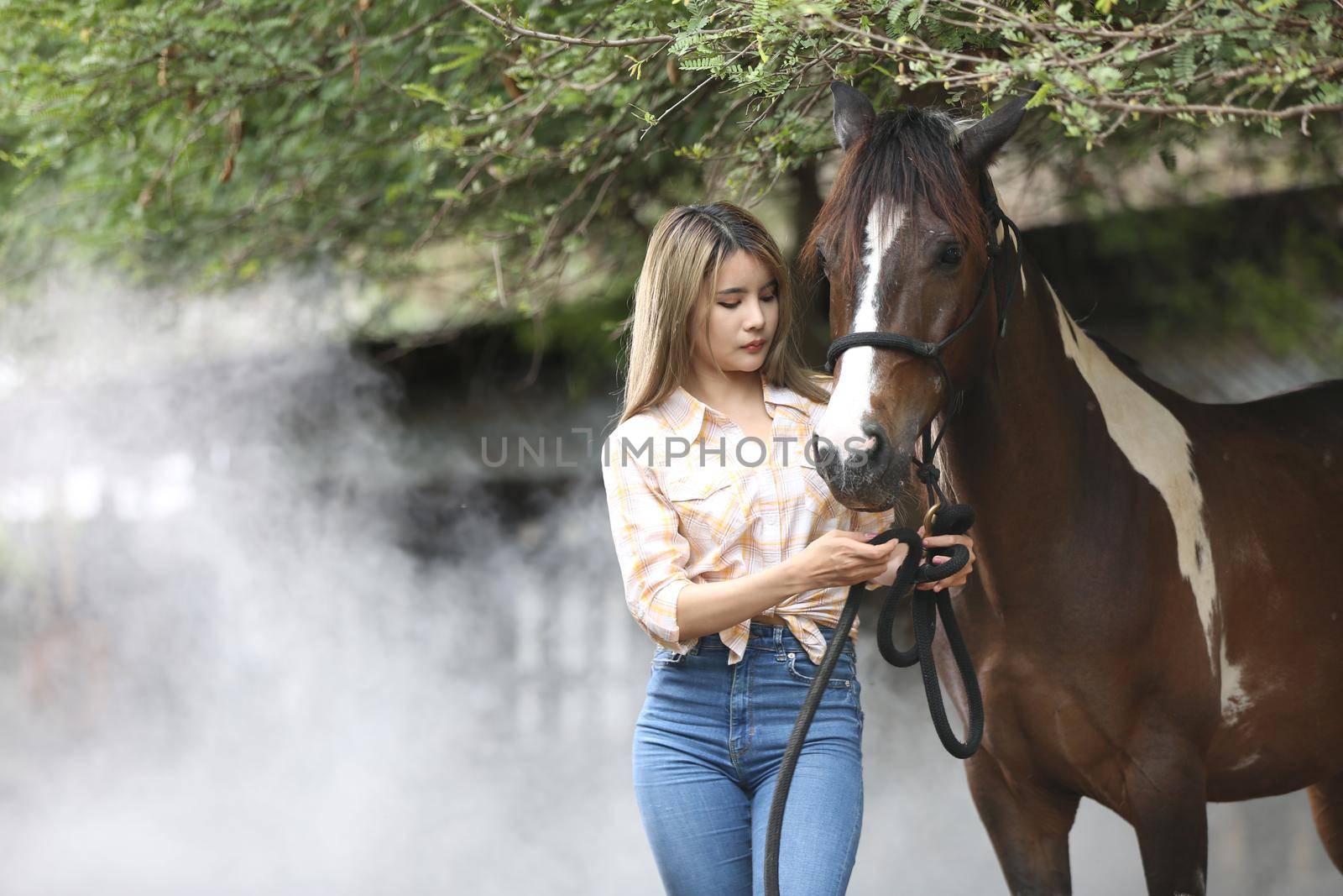 A woman in a cowgirl style sits in a horse ranch with a western farm environment.