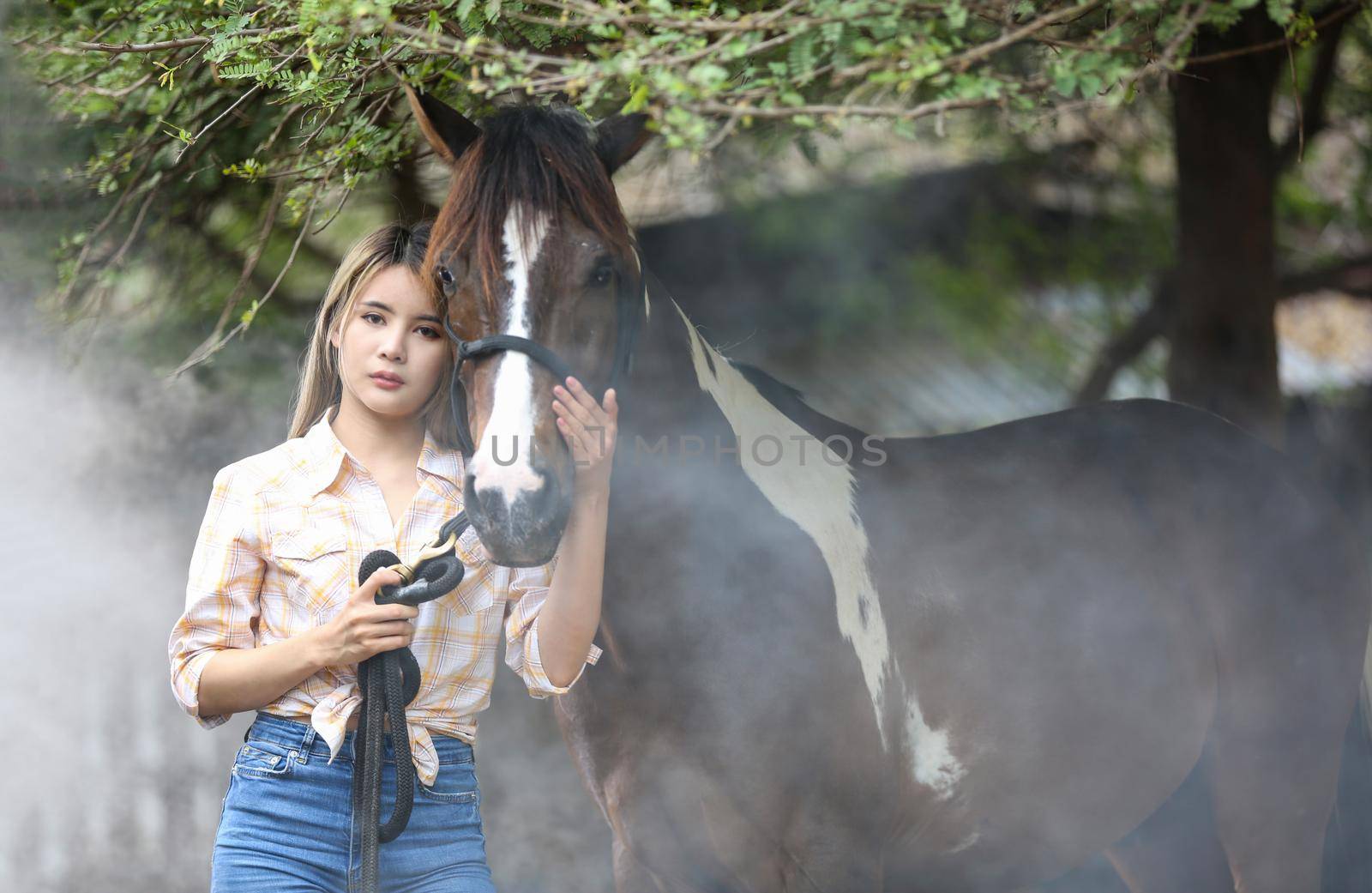 A woman in a cowgirl style sits in a horse ranch with a western farm environment.