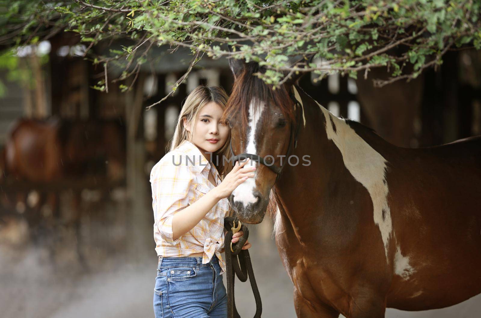 A woman in a cowgirl style sits in a horse ranch with a western farm environment.